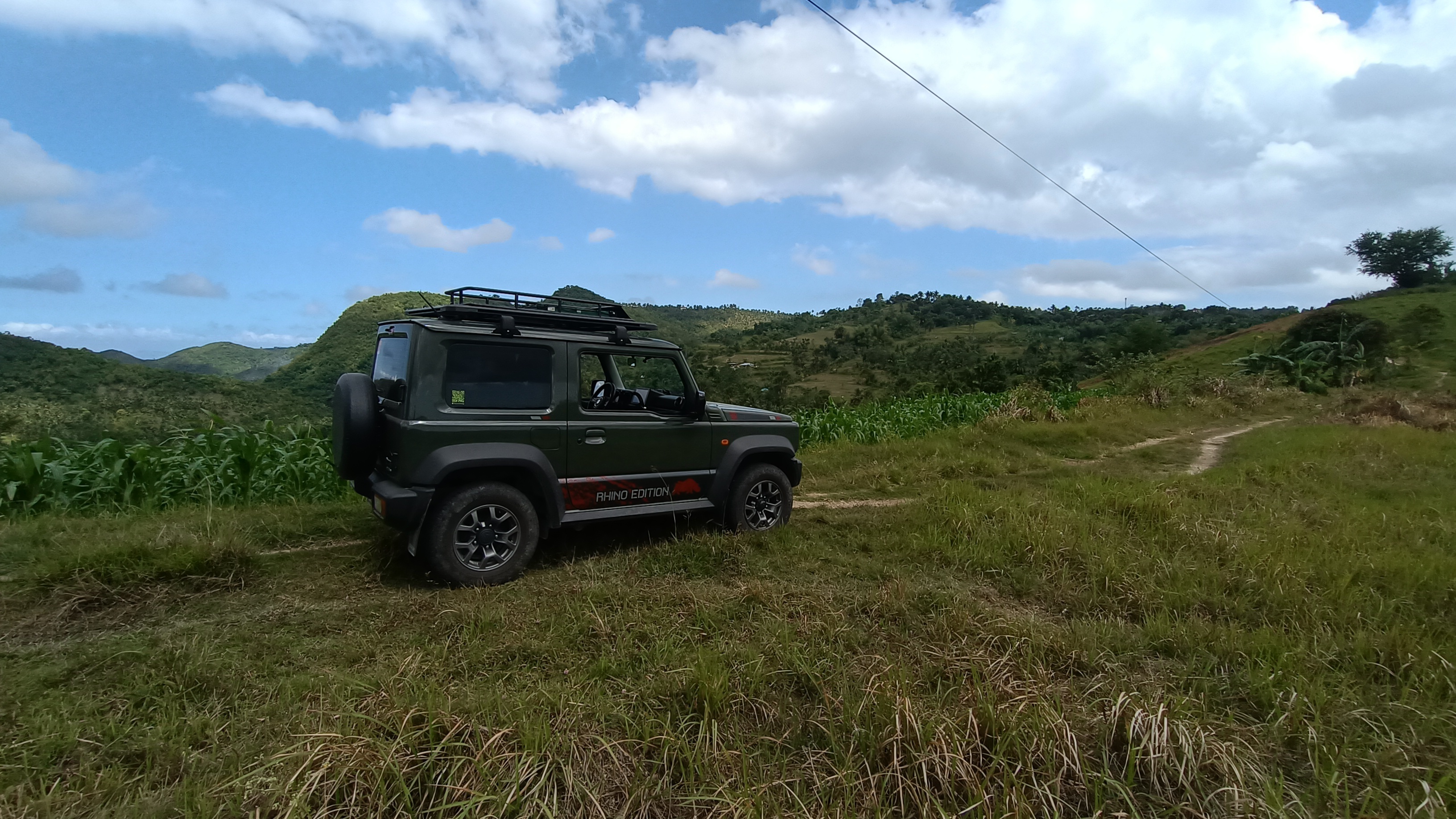 Jimny parked on a grassy hilltop clearing